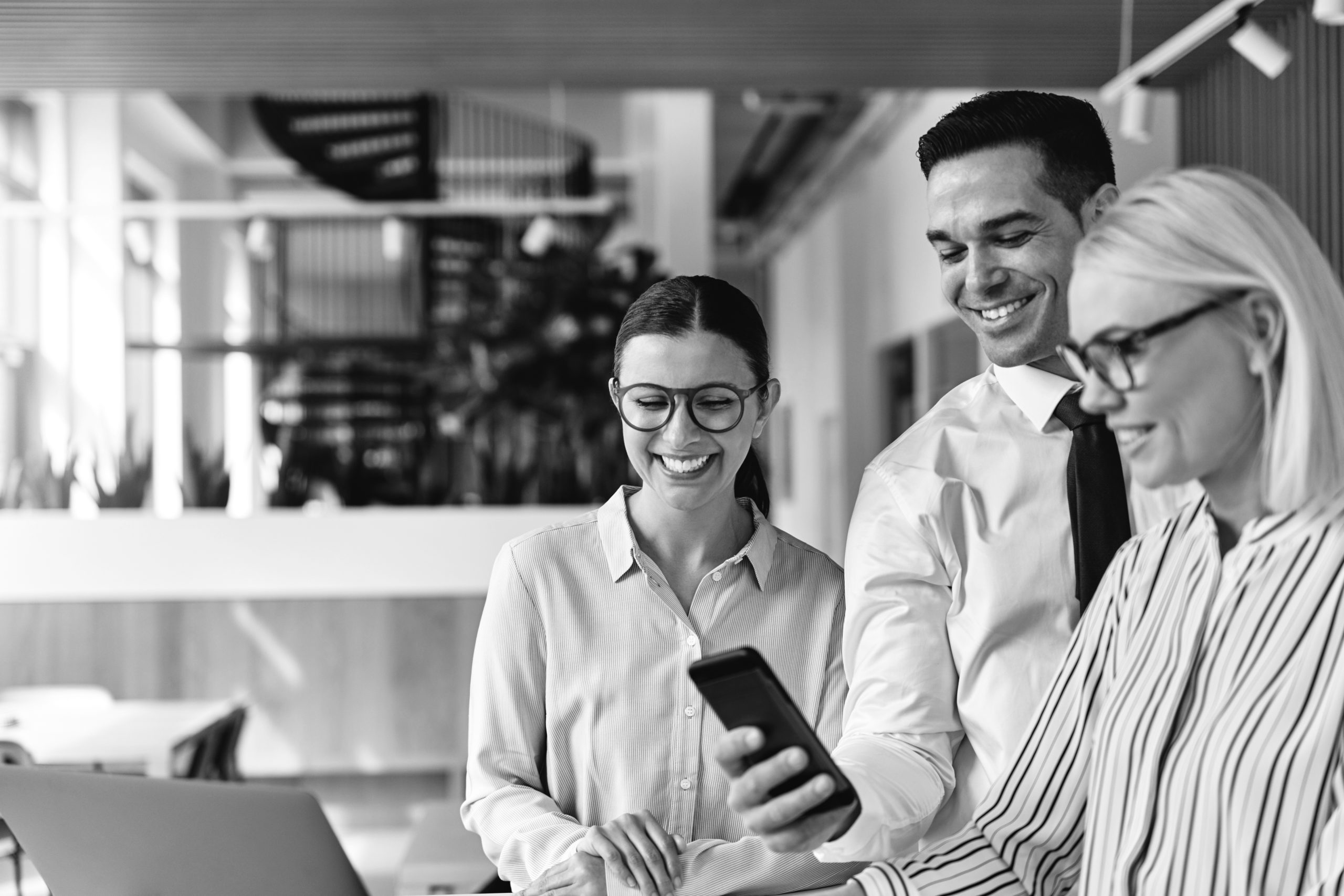 Soluções: Produção de conteúdo 5 three smiling businesspeople using a cellphone tog 2026 01 05 00 37 22 utc scaled